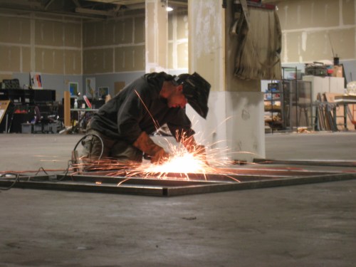 Gus is aglow in sparks as he works on one of FluxWagon's stage panels.